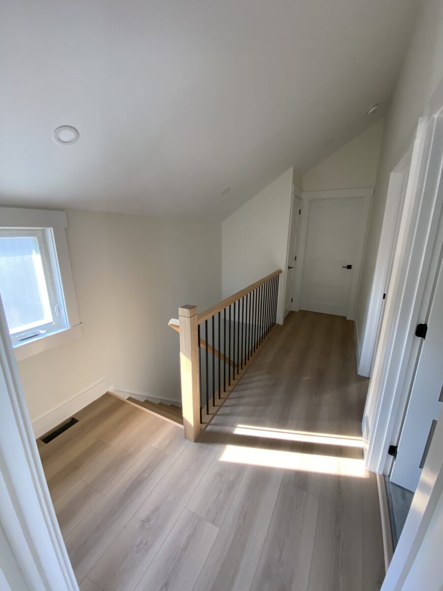A newly renovated staircase leading to a newly floored landing that incorporates a wood style flooring material.