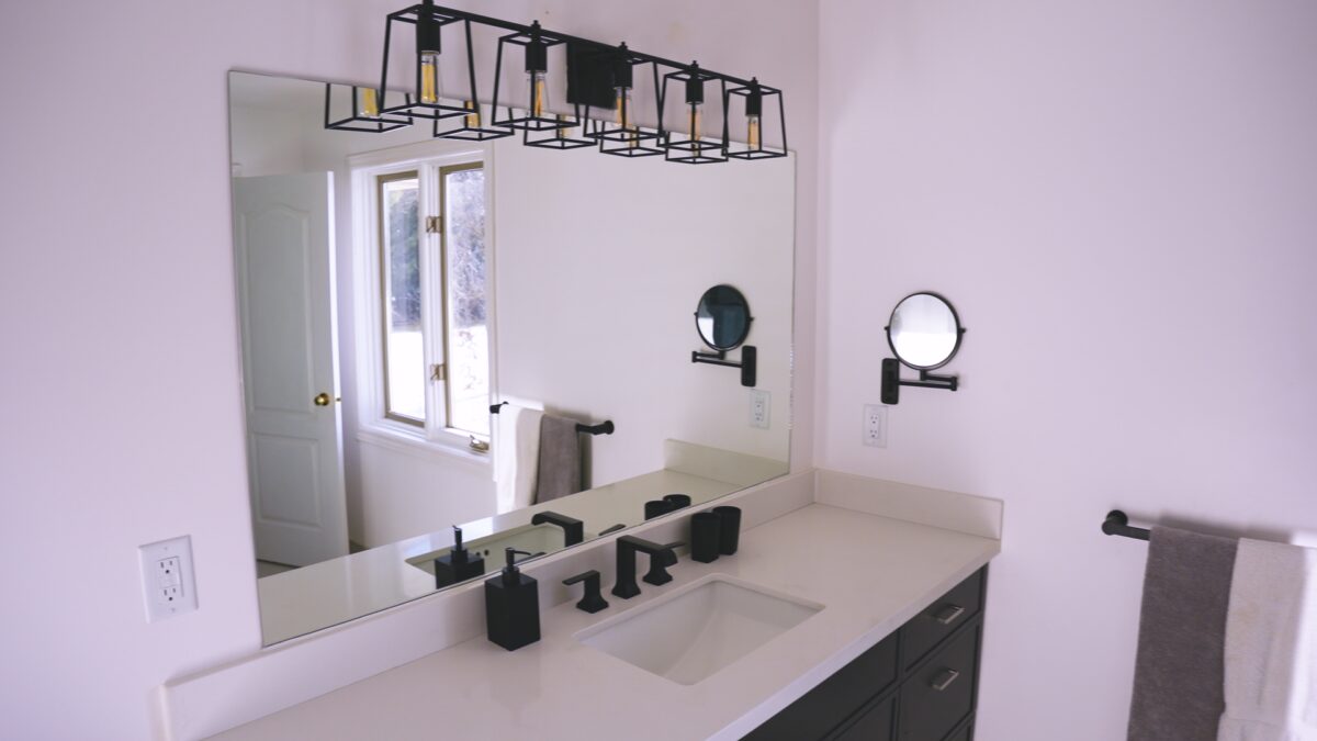 A newly renovated bathroom vanity, mirror and light fixture with black matte finish.