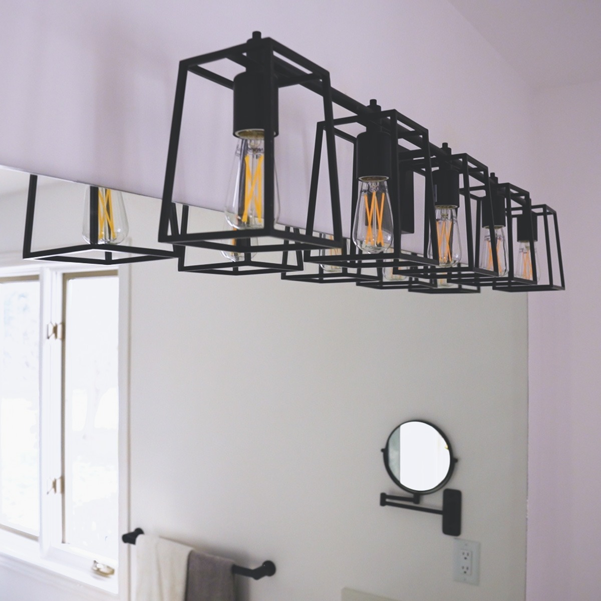 Five light, lighting fixture with matte black finish beside a mirror over a vanity, not pictured.
