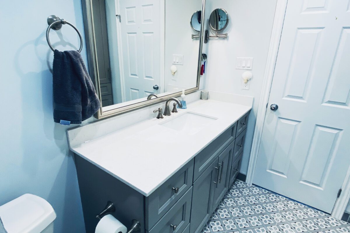 A bathroom vanity and mirror on a pattern, tile floor.