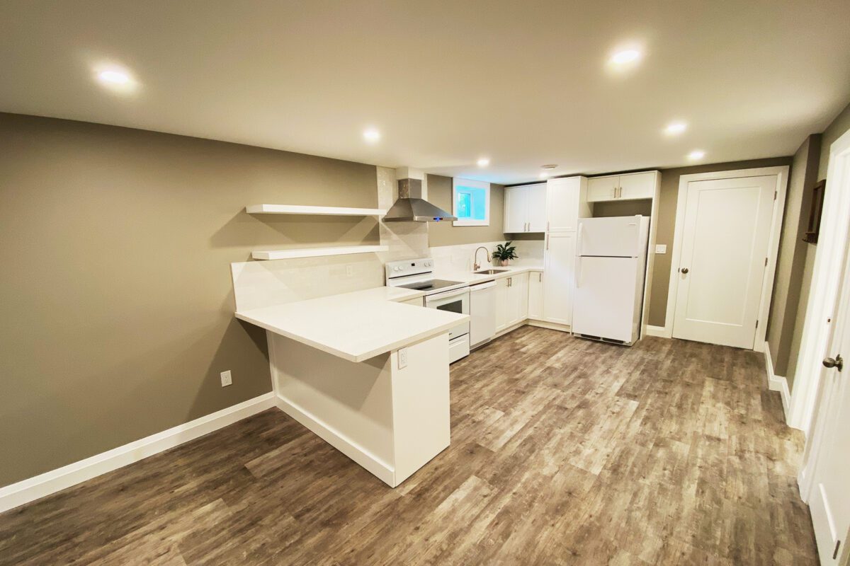 A full kitchen with open shelves and a rangehood in a newly finished basement.