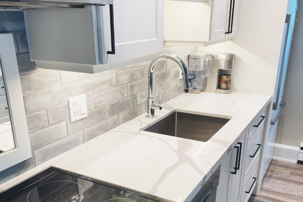 Looking down marble style countertop in a newly renovated kitchen, focused on the facet and sink.