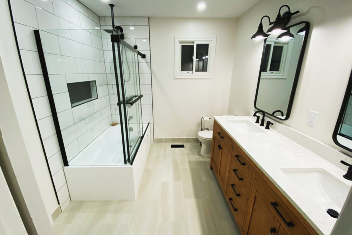 A full bathroom with a double vanity and bath tub with glass walls.