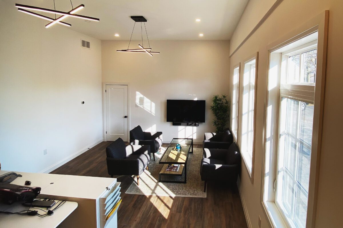 Inside an office entry room looking at a long table with chairs and a TV at the end of it.